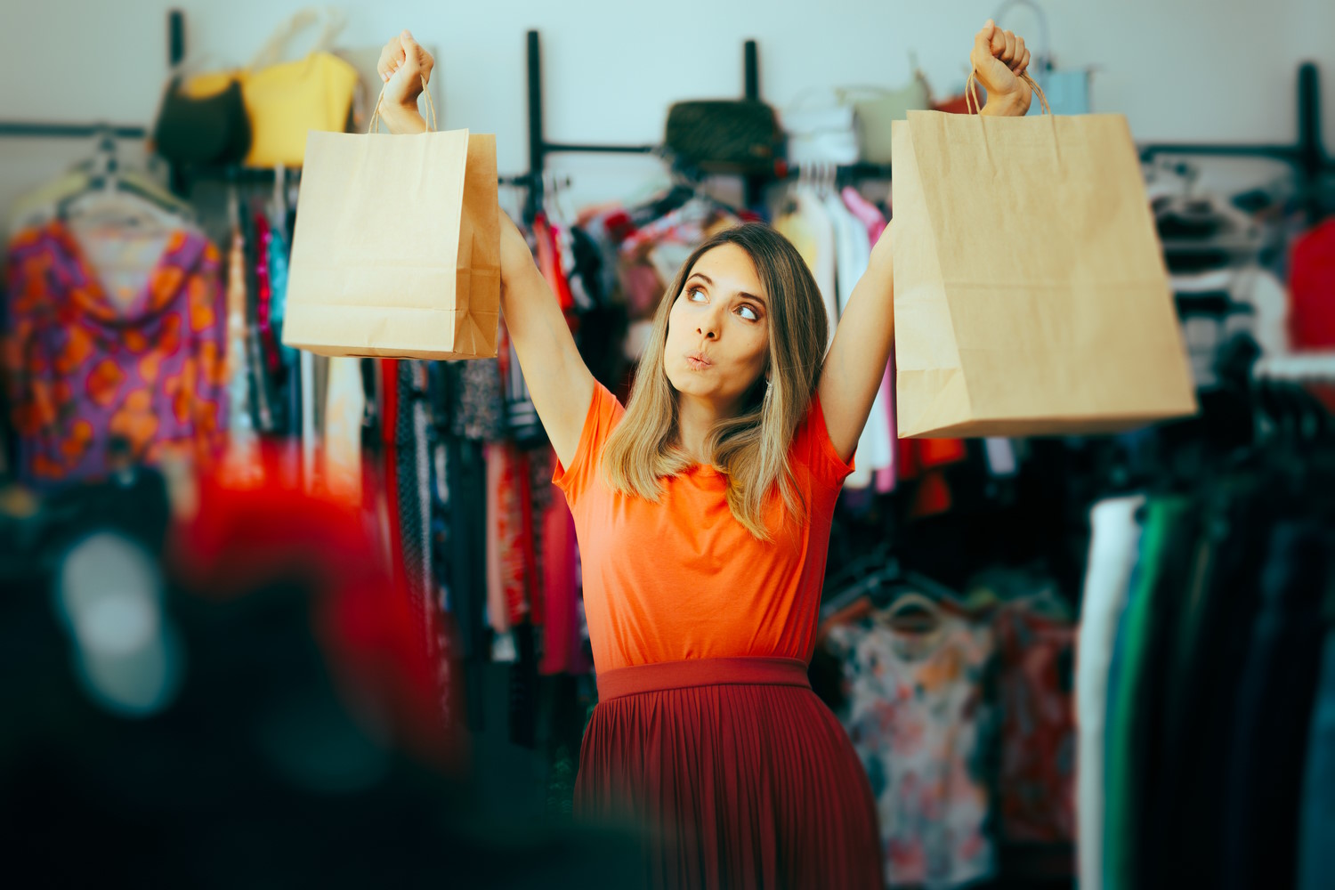 mujer levanta dos bolsas de ropa en medio de una tienda